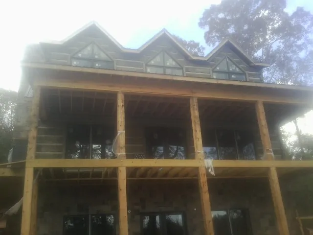 Dormers and porch framing on a large log home under construction — Roof Coating work by our crew in Huntington